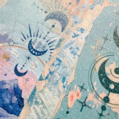 Decorative paper with celestial designs, including moons and stars, on a pastel background.